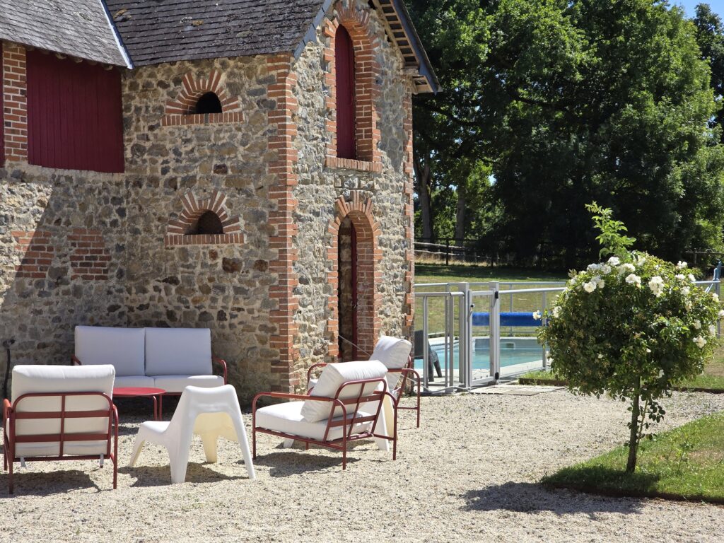 Ancien bâtiment en pierre rénové par TFL GROUPE en Mayenne, transformé en gîte de charme avec espaces extérieurs et piscine, illustrant la valorisation du patrimoine local.