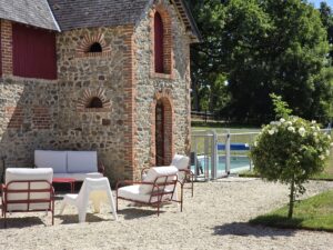 Ancien bâtiment en pierre rénové par TFL GROUPE en Mayenne, transformé en gîte de charme avec espaces extérieurs et piscine, illustrant la valorisation du patrimoine local.